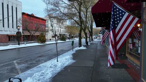 Static-aerial-shot-of-American-flags-during-white-Christmas-snow-storm