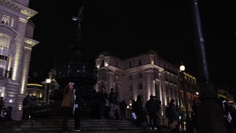 Pareja-De-Pie-En-El-Centro-De-Piccadilly-Circus-Frente-A-La-Fuente-Tomando-Un-Selfie-En-La-Noche