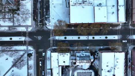 Top-down-aerial-truck-shot-of-main-street-in-small-town-decorated-for-Christmas-with-snow