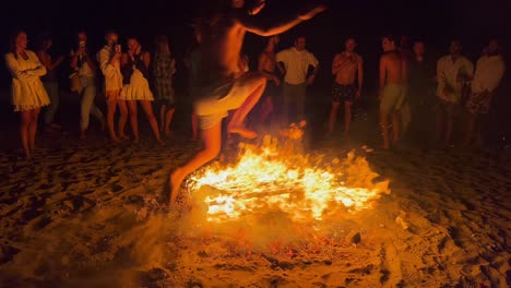 Gente-Saltando-Sobre-Una-Hoguera-Tradicional-En-El-Festival-De-San-Juan-En-La-Playa-De-Marbella-España,-Amigos-Y-Familiares-Disfrutando-De-Una-Fiesta-Divertida,-Saltando-Sobre-Un-Gran-Fuego-Ardiente-Y-Llamas-Calientes,-Tiro-De-4k