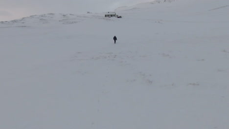 Niña-Camina-Sobre-La-Nieve-Hacia-La-Cabaña-Abandonada,-Día-De-Invierno