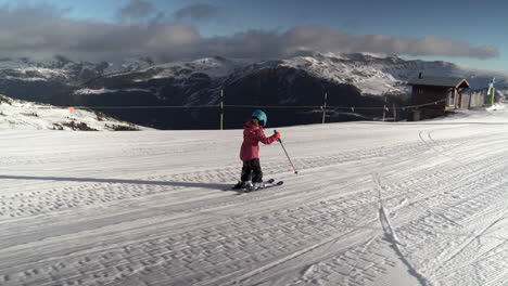 Young-child-skiing-snowy-sunlit-Andorra-resort-piste-with-amazing-views-of-Pyrenees-mountains
