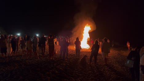 Gran-Multitud-En-El-Tradicional-Festival-De-Hogueras-En-La-Playa-En-La-Celebración-De-San-Juan-En-Marbella-España,-Amigos-Y-Familiares-Disfrutando-De-Una-Fiesta-Divertida-Durante-El-Verano,-Fuego-Ardiente-Y-Llamas-Calientes,-Tiro-De-4k