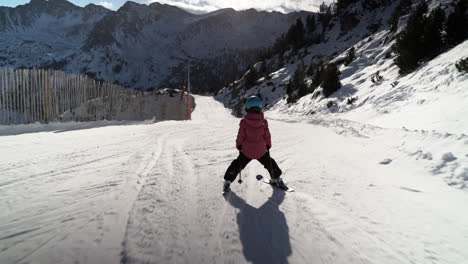 Child-learning-to-ski-downhill-on-snowy-mountain-resort-skiing-track