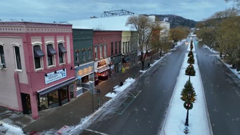 Snow-falling-on-small-American-town-street-lined-with-Christmas-trees-and-snow