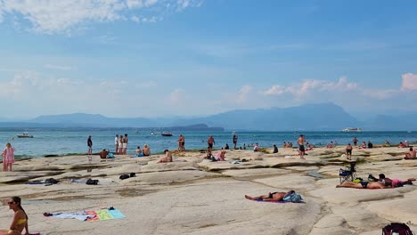 Turistas-Tomando-El-Sol-En-La-Playa-En-Sirmione,-Italia