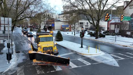 Snow-plows-and-trucks-drive-through-intersection-during-snowy-Christmas-morning-in-Wellsboro-Pennsylvania