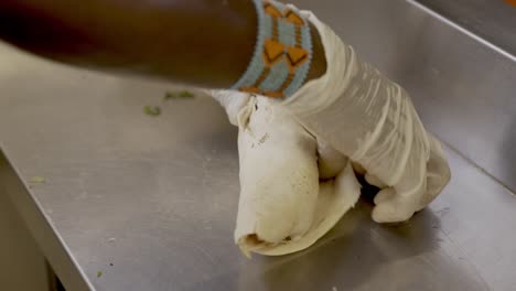Person,-Die-Weiße-Handschuhe-Trägt,-Die-Chiecken-Shawarma-Sandwich-Auf-Edelstahltisch-Einwickeln
