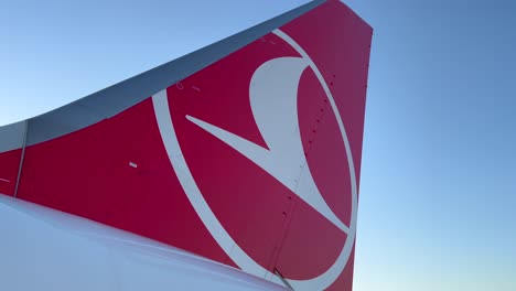 Turkish-Airlines-logo-on-an-airplane-wing-at-an-international-airport-in-Turkey-with-blue-sky,-4K-shot