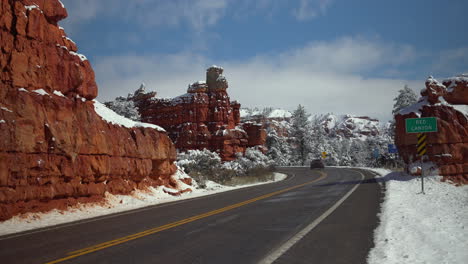 Car-Driving-Down-Snowy-Road-in-Red-Rock-Utah-Desert