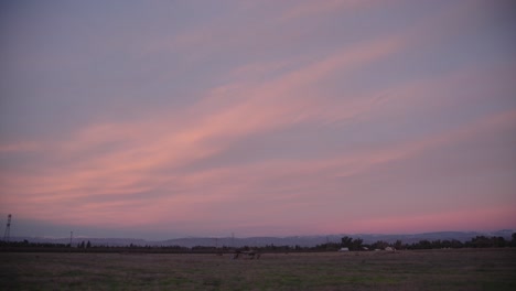 A-pastel-sky-over-the-Sierra-Nevada-mountains-with-power-lines-and-a-shed-in-the-foreground-in-Clovis,-CA,-USA