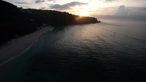 Playa-Escénica-En-La-Costa-De-Bali-Durante-La-Puesta-De-Sol,-Silueta-De-Ladera-Boscosa