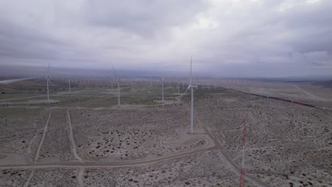 Aerial-footage-of-a-wind-farm-in-the-Palm-Springs-desert-on-a-cloudy-day,-slow-dolly-shot