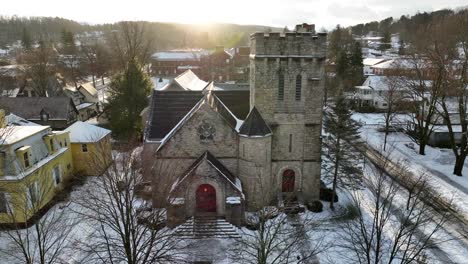Slow-aerial-tilt-up-of-gothic-church-building-on-snowy-day-with-moody-sunshine