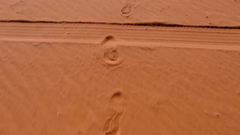 Footprints-left-in-red-sandy-desert-of-Wadi-Rum-in-Jordan,-Middle-East,-from-a-person-walking-through-the-vast,-remote-wilderness