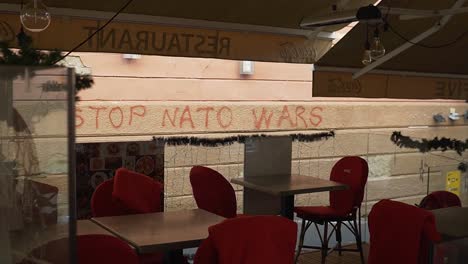 Leere-Tische-Und-Stühle-Im-Restaurant-Mit-Einer-Mit-Graffiti-Bemalten-Wand