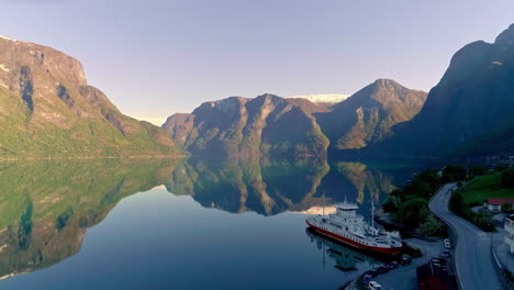 Ferry-docked-on-a-fjord-in-Norway-with-the-water-surface-reflecting-the-sky-and-landscape