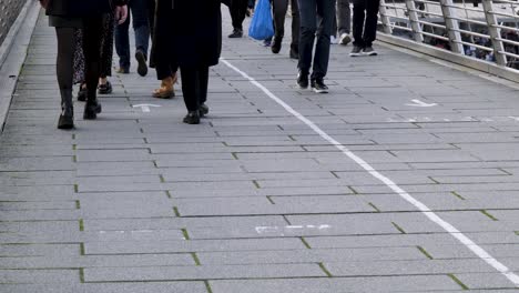 Close-up-of-pedestrians-crossing-the-Millennium-Bridge-over-the-Thames