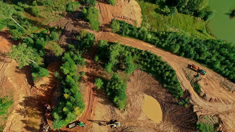 Aerial-top-down-shot-of-wood-clearing-in-nature,-trucks-transporting-cut-wood-trunks---Industrial-construction-site-in-nature