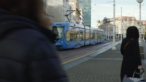 Tram-moving-through-the-city-and-peole-walking-towards-the-square-of-Ban-Jelacic-in-Zagreb,-Croatia