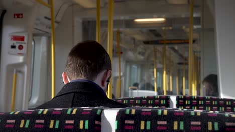 13-January-2023---View-Behind-Commuter-Sitting-On-Metropolitan-Line-Train-Wearing-Earphones