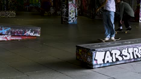 Ein-Skateboarder-Macht-Einen-Sprung-Als-Leute,-Die-Im-Skatepark-Southbank-Centre,-London,-Großbritannien,-Skateboard-Fahren