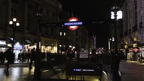 People-walking-at-night-next-to-entrance-to-Public-Subway-Underground-Station-Piccadilly-Circus-in-London-Downtown
