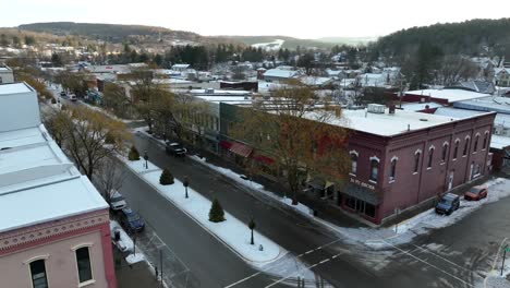 Aerial-orbit,-reveal-of-main-street-of-Wellsboro-Pennsylvania-decorated-for-Christmas-on-snowy-winter-day