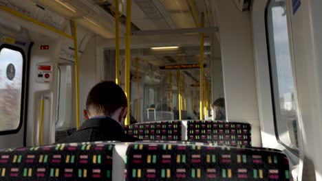 13.-Januar-2023---Blick-Hinter-Den-Passagier,-Der-Auf-Dem-Metropolitan-Line-Train-Sitzt-Und-Kopfhörer-Trägt