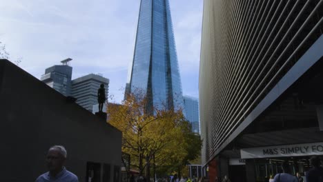 La-Gente-Camina-Mientras-Se-Ve-La-Torre-De-Fragmentos-Desde-Abajo-En-La-Ciudad-Del-Puente-De-Londres,-Al-Suroeste-Del-Puente-De-La-Torre-En-Londres