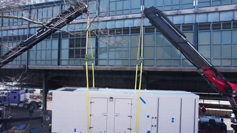 Drone-Shot-of-Two-Cranes-Holding-Up-Big-AC-Unit,-Preparing-to-Lift-Up-on-Top-of-The-Building-in-Brooklyn,-New-York-USA