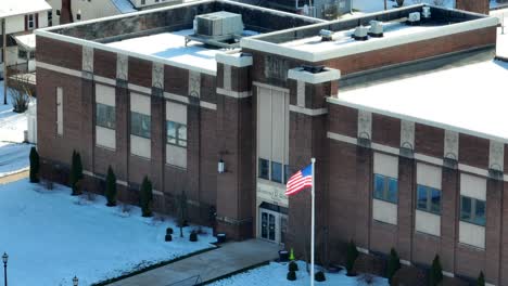 Enger-Luftzoom-Der-Amerikanischen-Flagge,-Die-Vor-Der-Backsteinschule-Weht