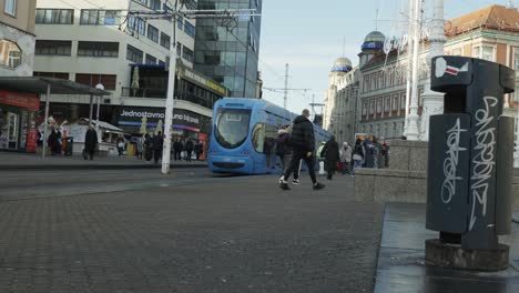 People-walking-in-and-out-the-tram-at-the-station-of-Ban-Jelalic-in-Zagreb,-Croatia