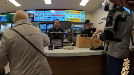 Der-Mitarbeiter-Von-Burger-King-Bedient-Einen-Lebensmittelkurier,-Der-Im-Servicebereich-Eine-Papiertüte-Mit-Fast-Food-Abholt---Brüssel,-Belgien