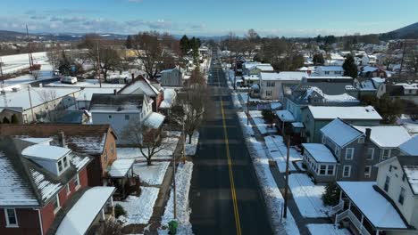 Slow-aerial-dolly-forward-over-plowed-street-in-snow-covered-neighborhood