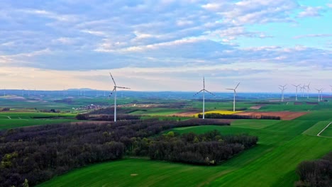 Aerial-View-Of-Agricultural-Landscapes-With-Windmills-Under-Cloudy-Blue-Sky