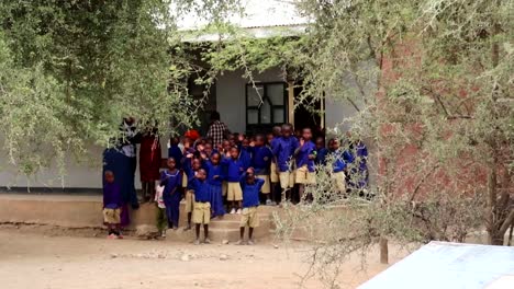 African-school-children-with-blue-uniforms-waving-saying-goodbye,-Tanzania