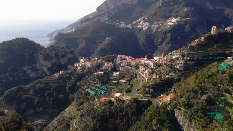 Mediterranean-Amalfi-town-aerial-view-down-lush-mountain-valley-towards-Italian-waterfront-seascape