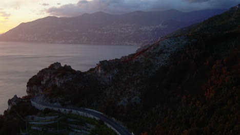 Italian-Amalfi-town-rocky-mountain-cliff-road-aerial-view-reveal-Mediterranean-sunset-seascape-coastline