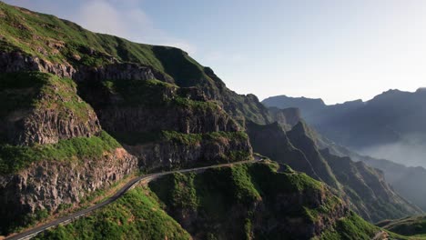 Aerial-view-of-mountain-road-pass-on-ridge-with-lush-green-vegetation,-Madeira