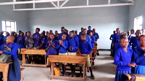 African-kids-in-blue-uniforms-in-a-rural-school-singing-and-clapping,-traditional-Swahili-songs-in-school