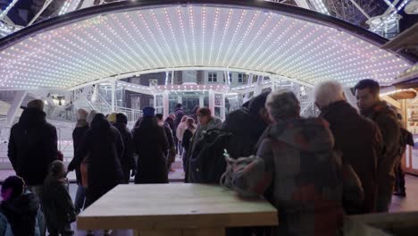 line-of-people-waiting-for-LED-lit-ferris-wheel-at-night-on-a-Christmas-market