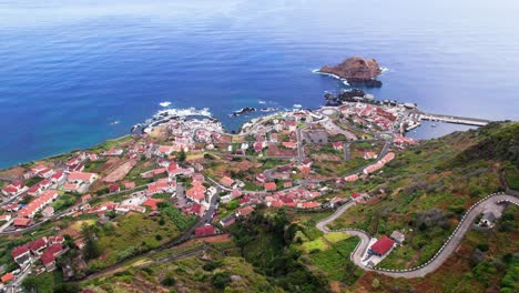 Aerial-view-of-Porto-Moniz-city-on-lush-green-volcanic-coast,-Madeira
