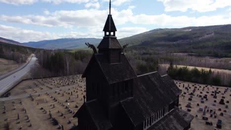 Aerial-view-orbiting-closely-around-a-stave-church-tower,-spring-day-in-Uvdal,-Norway