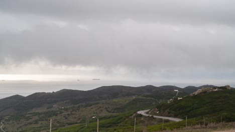Gibraltar-straight-with-rolling-clouds-in-low-altitude-and-winding-road,-time-lapse