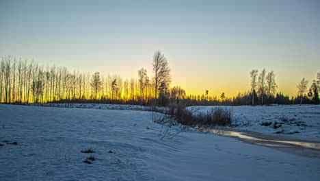 Bright-yellow-sun-setting-down-behind-winter-landscape,-fusion-time-lapse