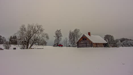 Timelapse-of-clouds-moving-fast-over-snowy-landscape-with-isolated-winter-wooden-cottage-in-background