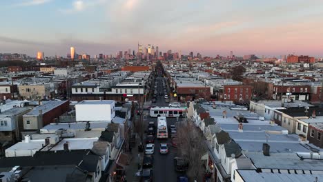High-aerial-reveal-pull-back-of-buses-driving-in-South-Philadelphia-during-winter-sunset