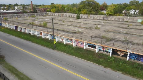 Old-derelict-water-reservoir-near-asphalt-road-in-Detroit,-pan-right-view