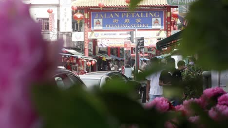 Chinatown-with-Petaling-street-sign,-crowded-location-in-Kuala-Lumpur,-seen-through-flowers